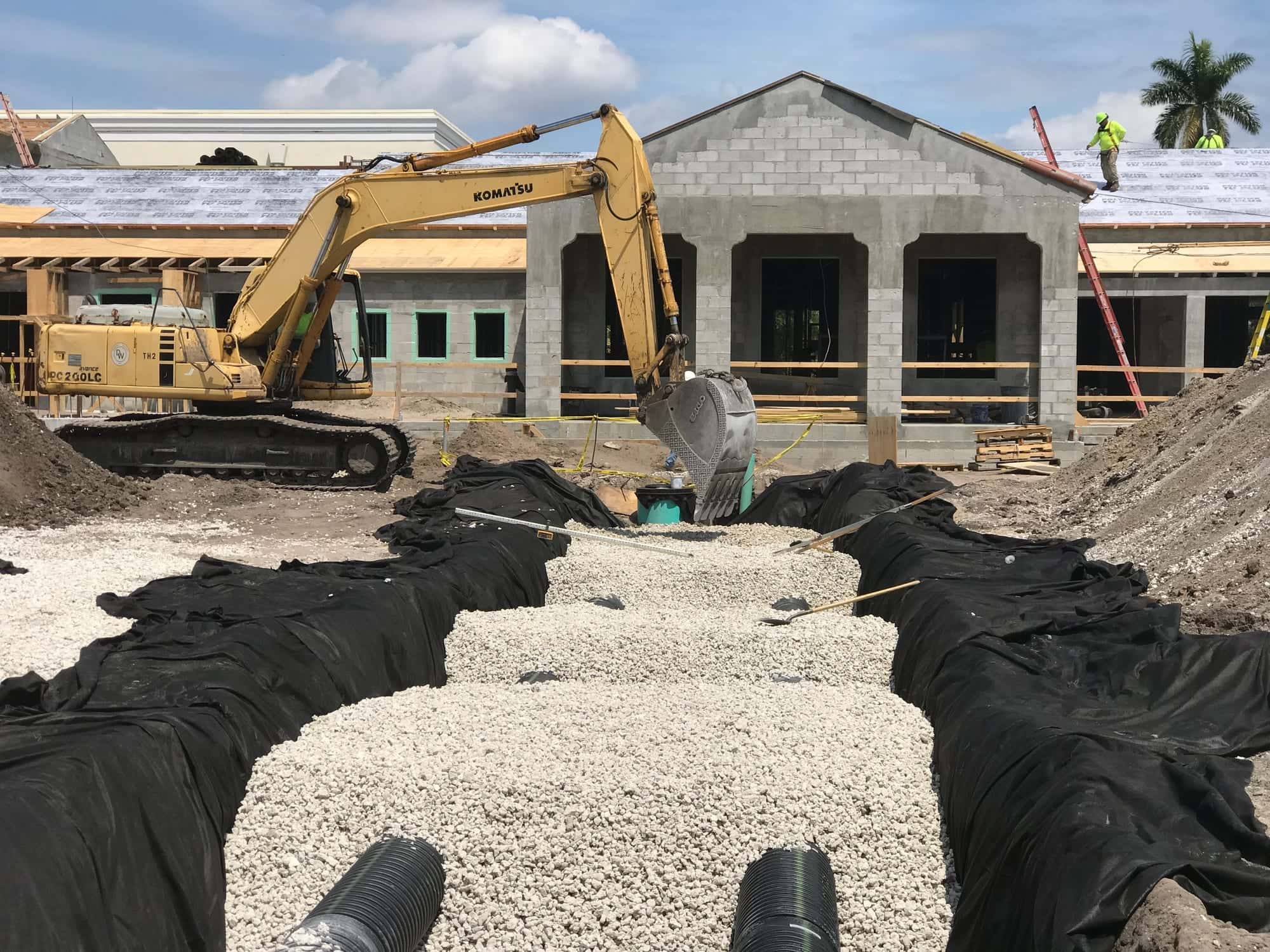 Concrete block commercial building under construction in Palm Beach County, with site drainage being installed